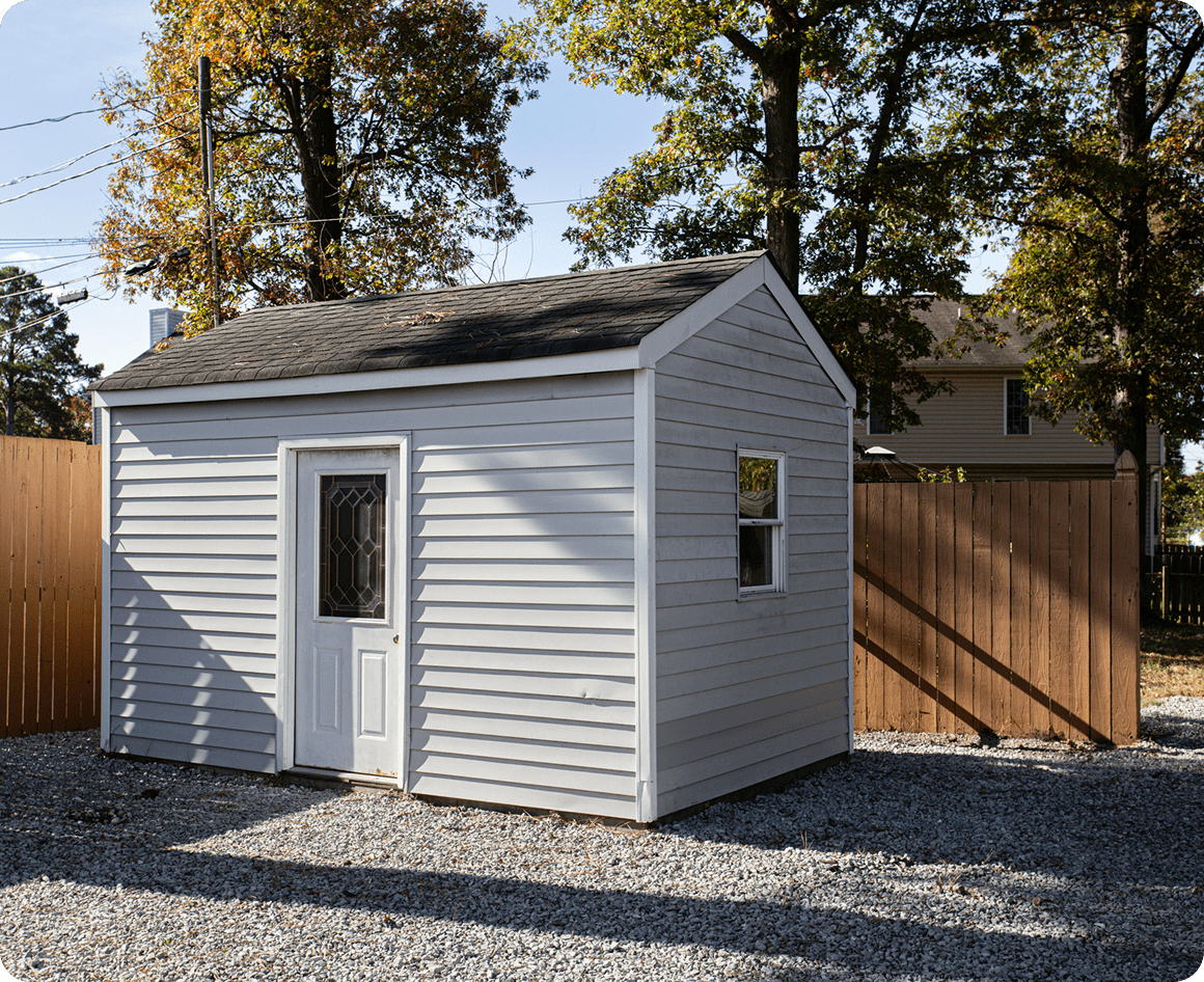 Grey shed in a fenced backyard.
