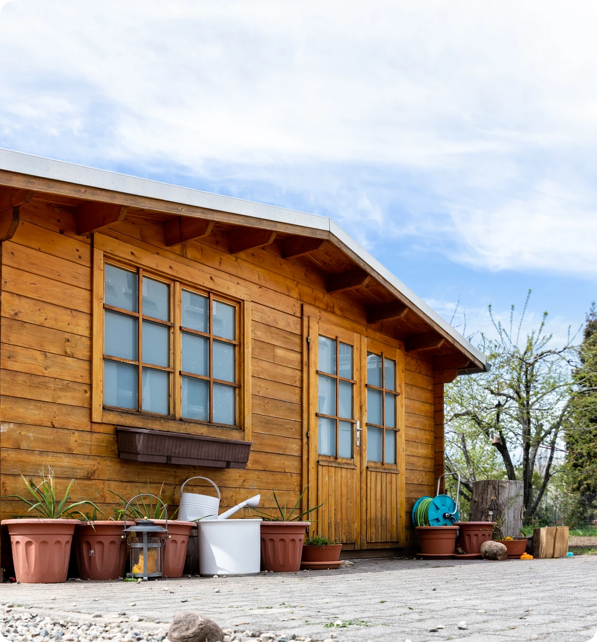 Wooden cabin with potted plants outside.